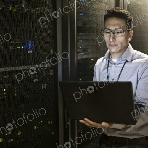 Hispanic man technician doing diagnostic tests on computer servers in a large server farm. Hispanic man technician doing diagnostic tests on computer servers in a large server farm.