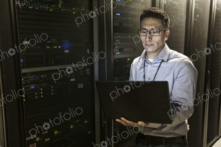 Hispanic man technician doing diagnostic tests on computer servers in a large server farm.