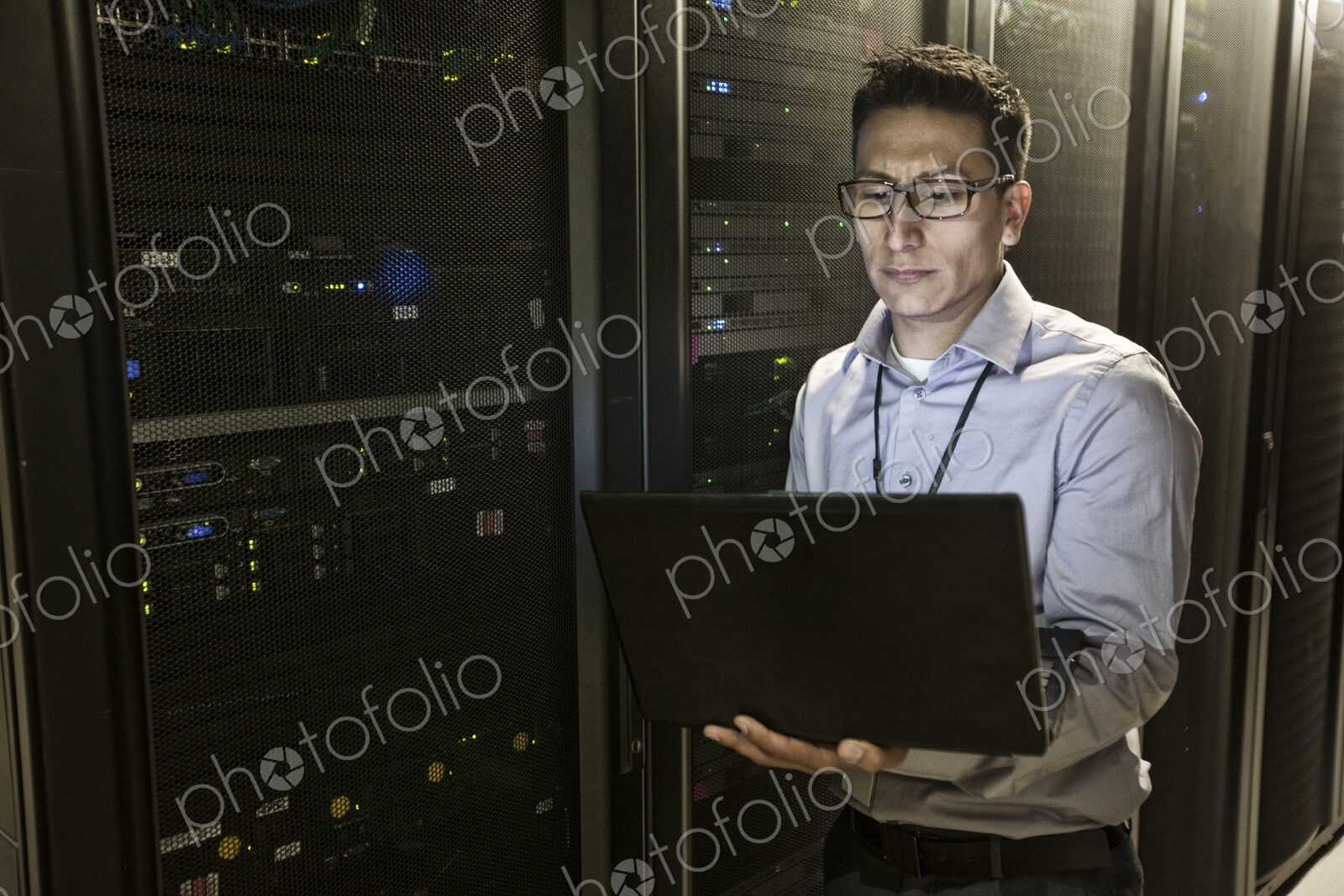 Hispanic man technician doing diagnostic tests on computer servers in a large server farm.