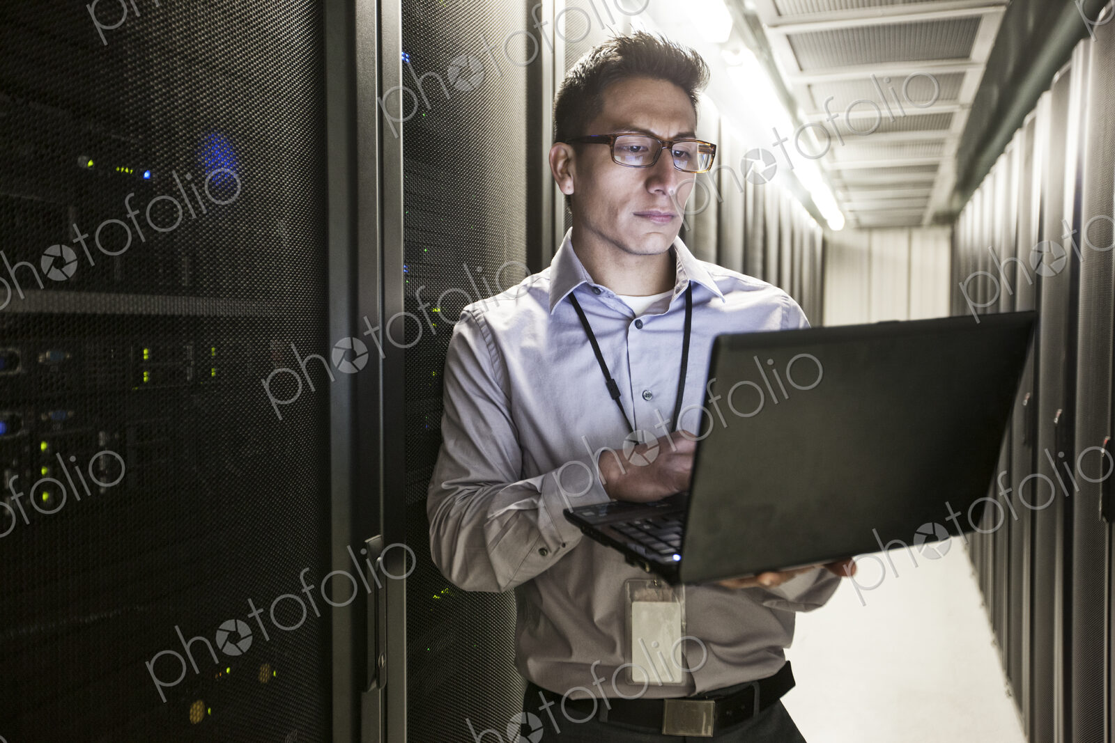 Hispanic man technician doing diagnostic tests on computer servers in a large server farm.
