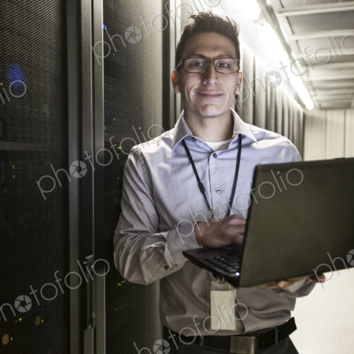 Hispanic man technician doing diagnostic tests on computer servers in a large server farm. Hispanic man technician doing diagnostic tests on computer servers in a large server farm.