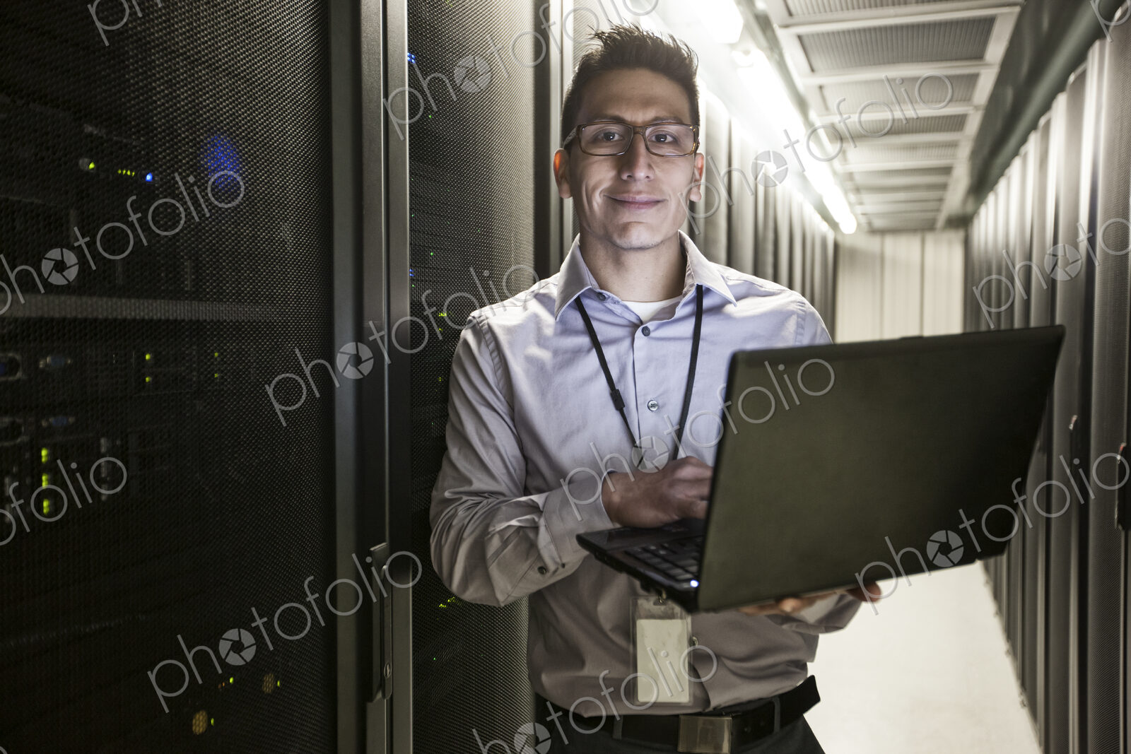Hispanic man technician doing diagnostic tests on computer servers in a large server farm.