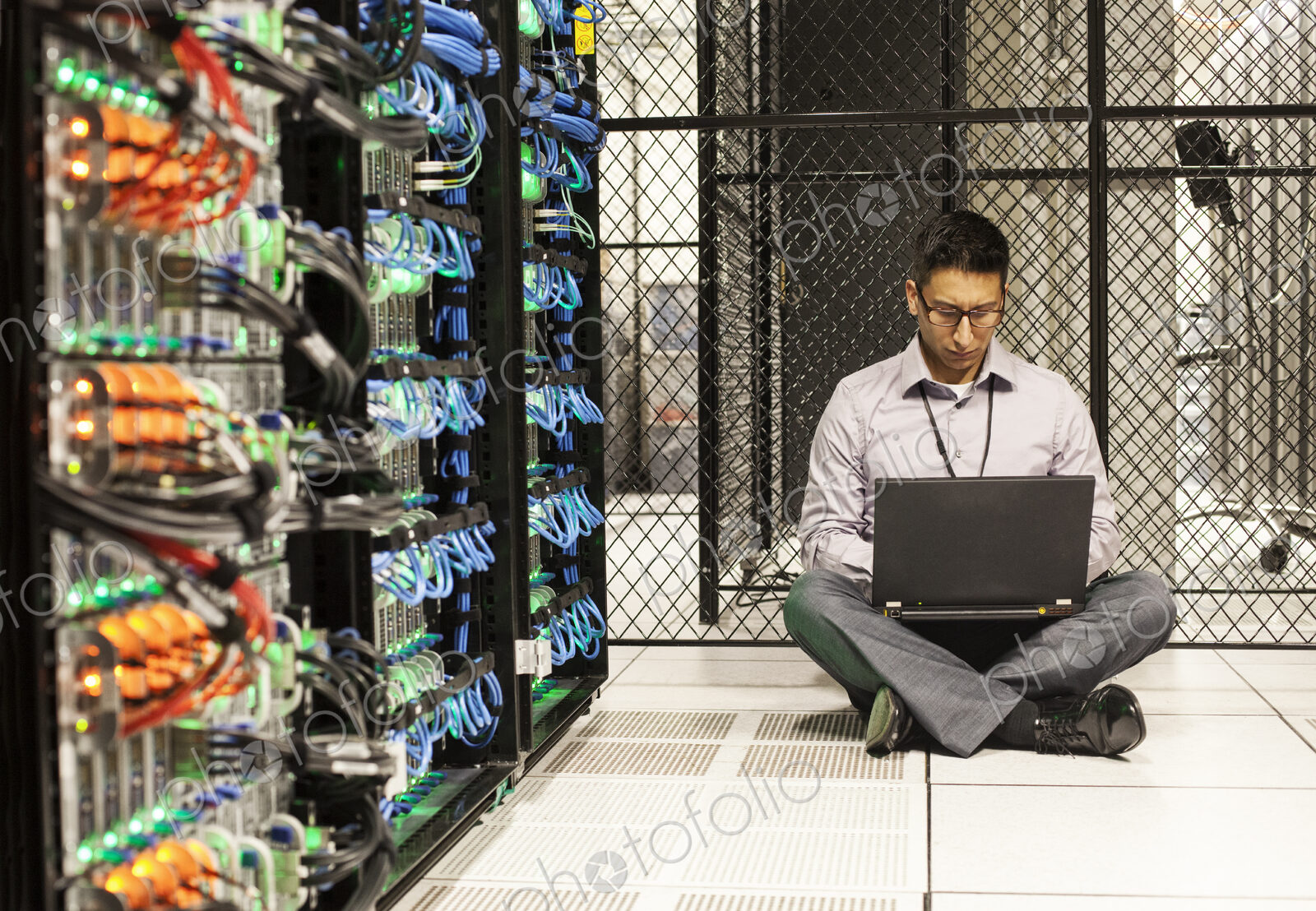 Hispanic man technician doing diagnostic tests on computer servers in a large server farm.