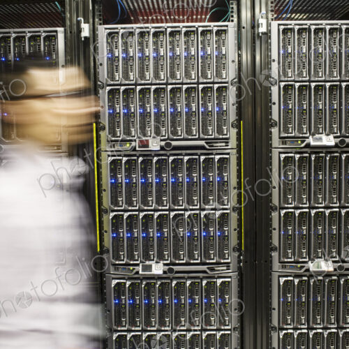 Hispanic man technician doing diagnostic tests on computer servers in a large server farm. Hispanic man technician doing diagnostic tests on computer servers in a large server farm.