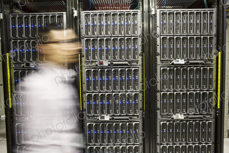 Hispanic man technician doing diagnostic tests on computer servers in a large server farm.