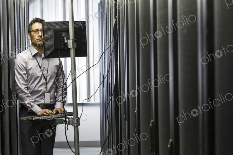 Hispanic man technician doing diagnostic tests on computer servers in a large server farm.