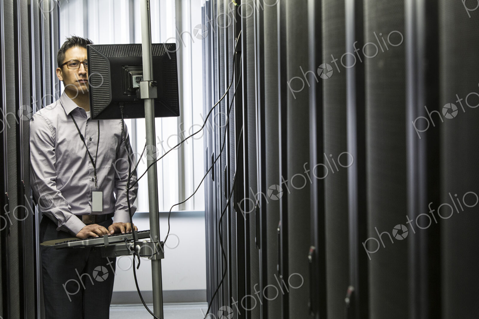 Hispanic man technician doing diagnostic tests on computer servers in a large server farm.
