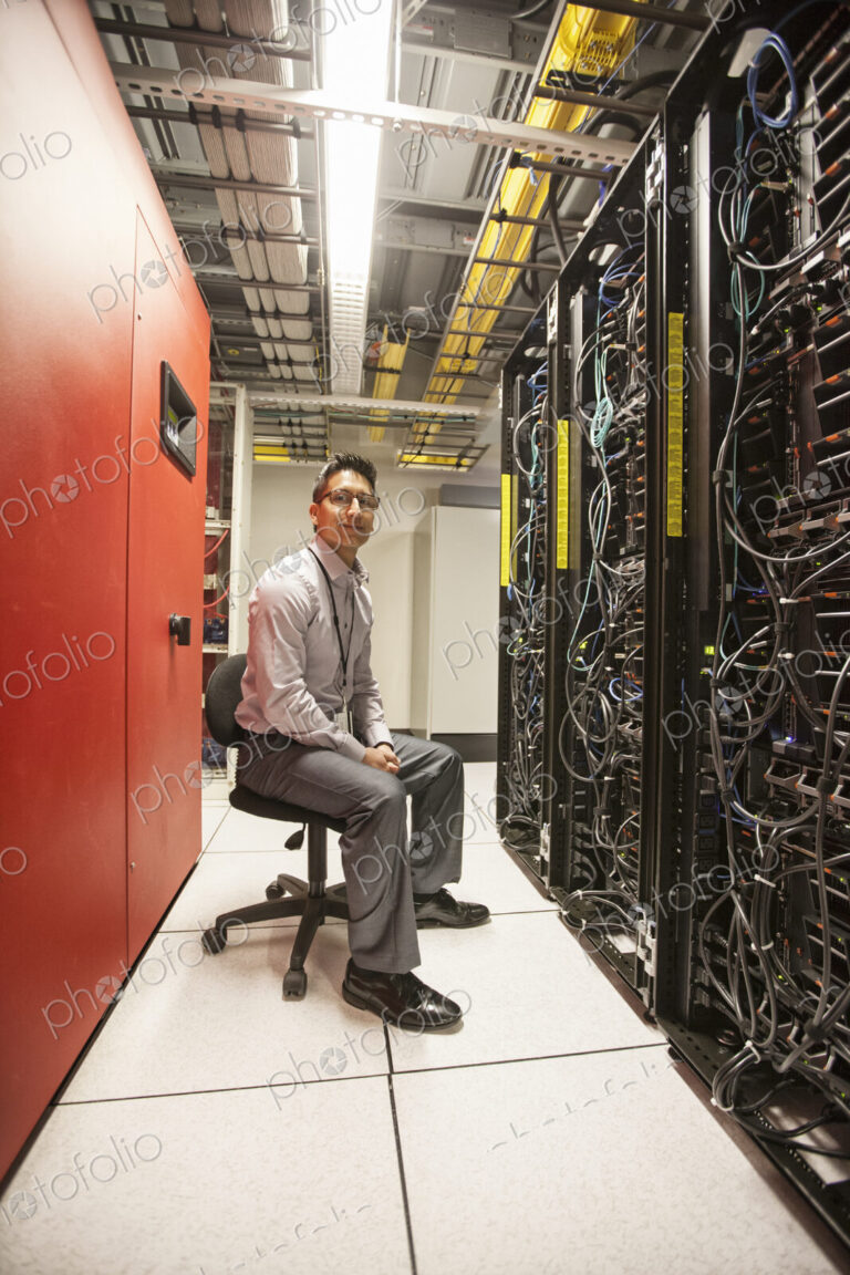 Hispanic man technician working with computer servers in a computer server farm.