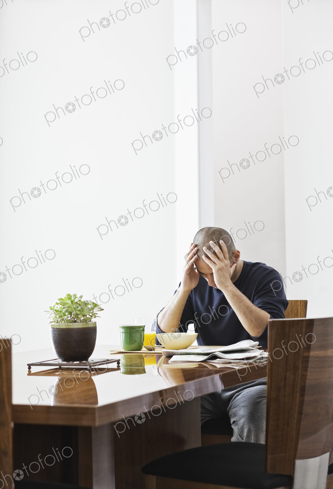 Hispanic man under stress while sitting at the dining room table in a new home.