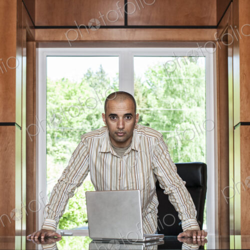 Hispanic man working on a laptop computer in his home office. Hispanic man working on a laptop computer in his home office.