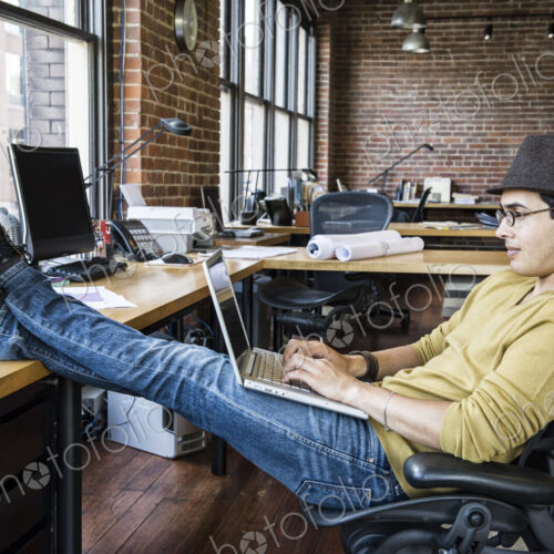 Hispanic man working on his laptop computer at this creative office work station.