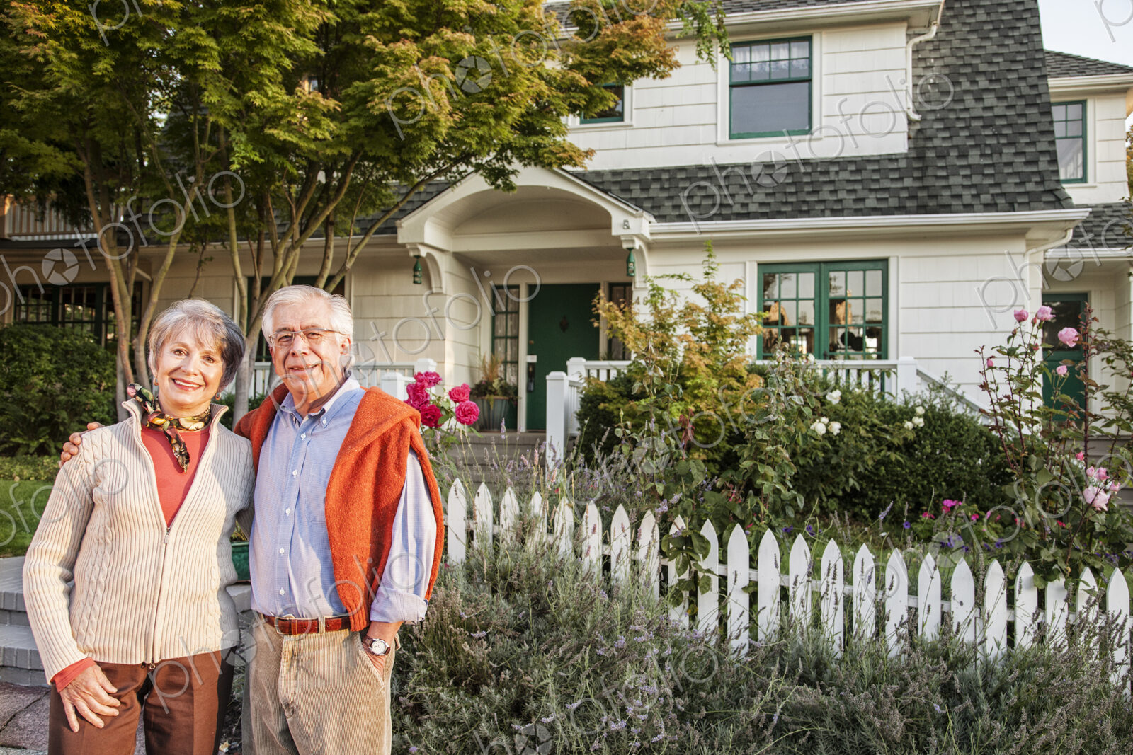 Hispanic senior couple in front of their remodeled older style home.