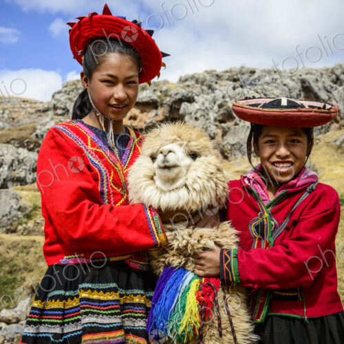 Hispanic sisters smiling with llama in rural landscape Hispanic sisters smiling with llama in rural landscape