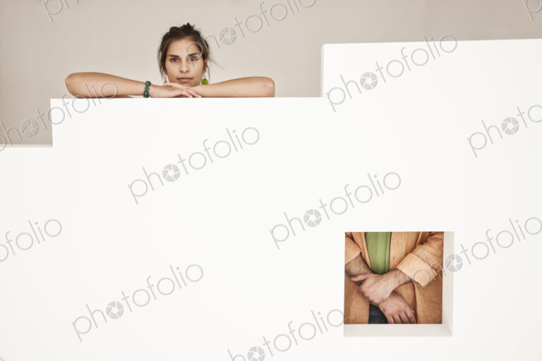Hispanic woman and man viewed from two viewpoints in a low wall with a square opening.