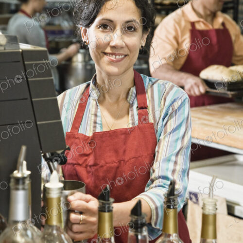 Hispanic woman at the cash register of a bakery/coffee shop. Hispanic woman at the cash register of a bakery/coffee shop.