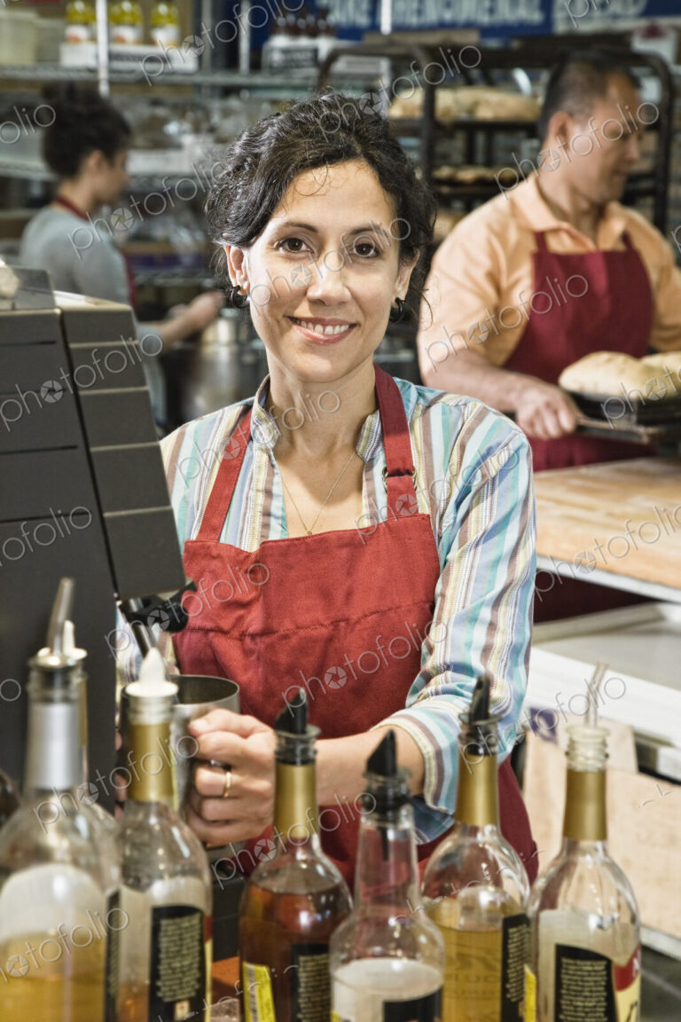 Hispanic woman at the cash register of a bakery/coffee shop.