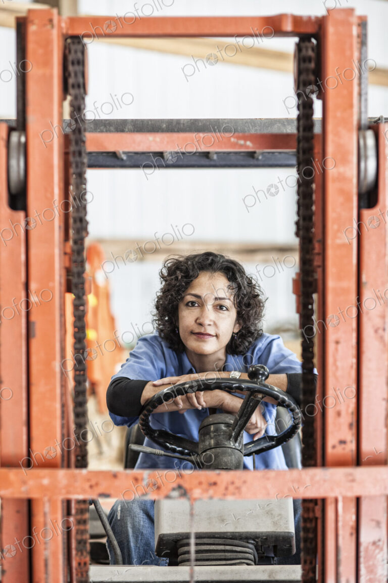 Hispanic woman employee using a forklift in a landscape company.