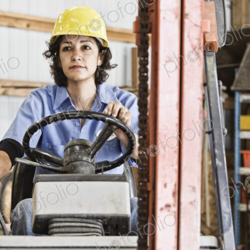 Hispanic woman employee using a forklift in a landscape company. Hispanic woman employee using a forklift in a landscape company.