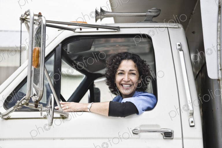Hispanic woman truck driver and company delivery truck.
