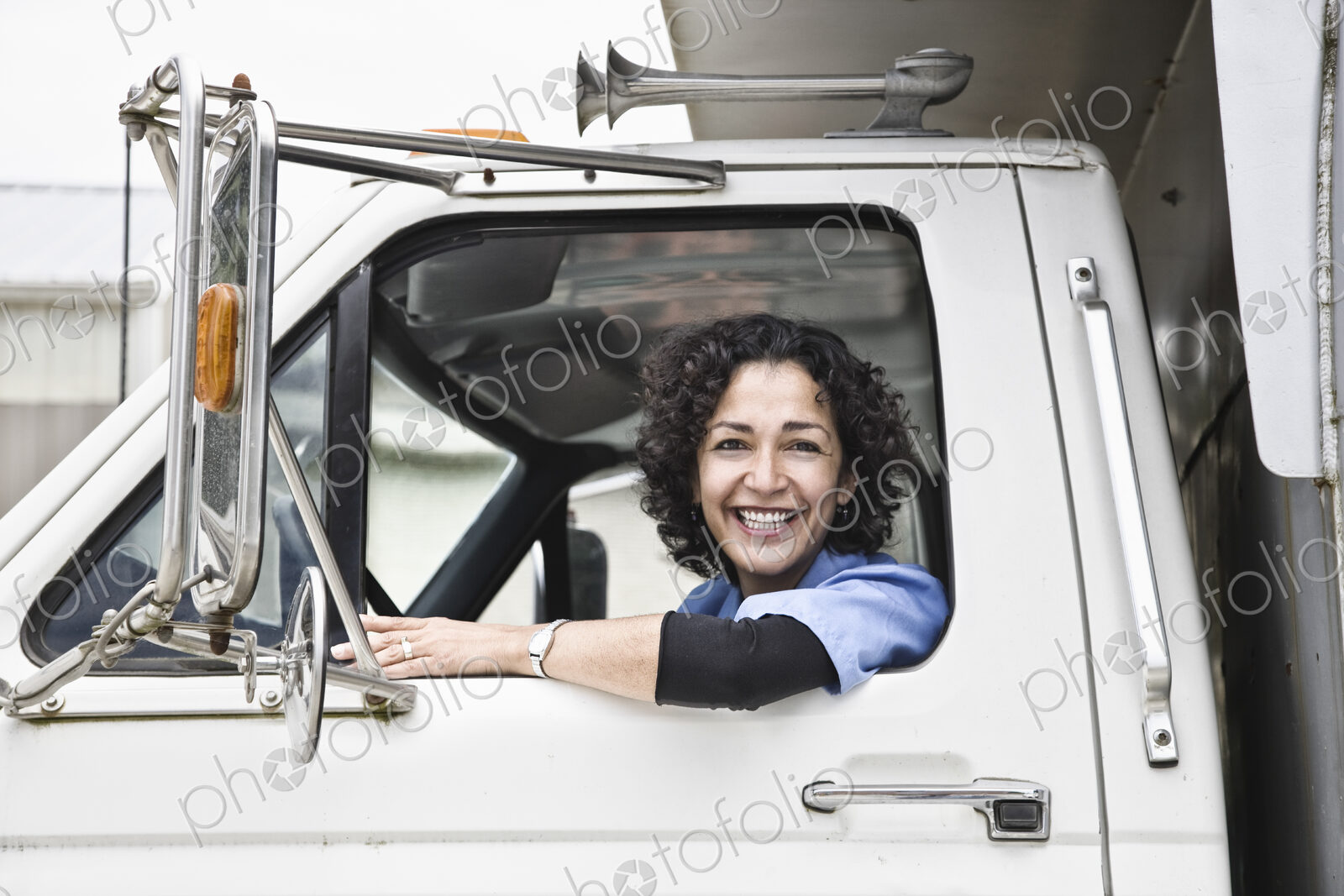 Hispanic woman truck driver and company delivery truck.