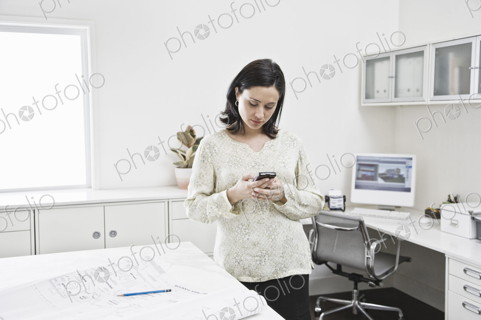 Hispanic woman working on cell phone in an architect’s office