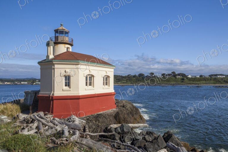 Historic Coquille River Lighthouse in Bandon, Oregon, stands on rocky shore with…