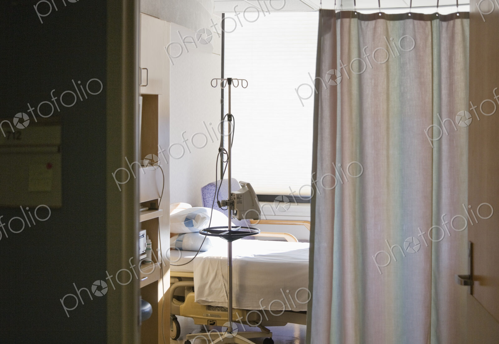 Hospital room with bed and privacy curtain.
