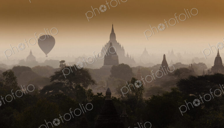 Hot-air balloon floats through the hazy skies of Bagan, Myanmar