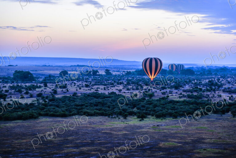 Hot air balloon flying over savanna landscape