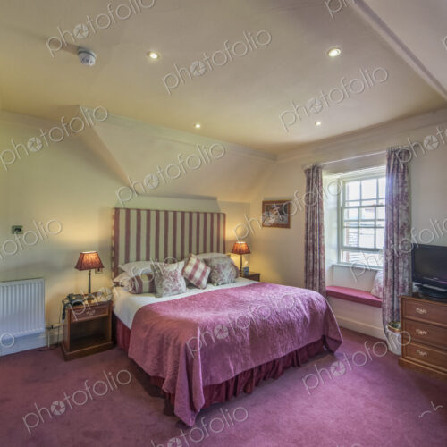 Hotel bedroom with taditional decor and sloped ceiling. Hotel bedroom with taditional decor and sloped ceiling.