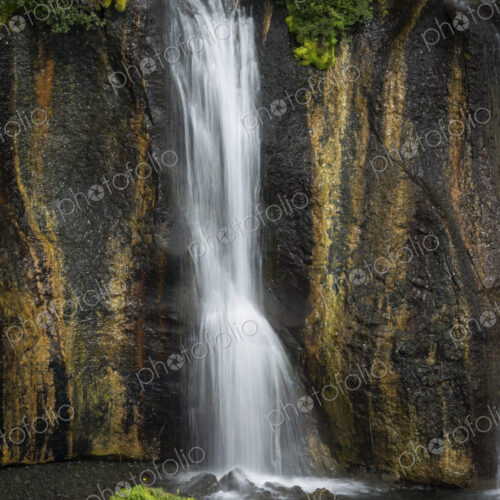 Hraunfossar waterfalls, a cascade of water over a sheer cliff into a pool.