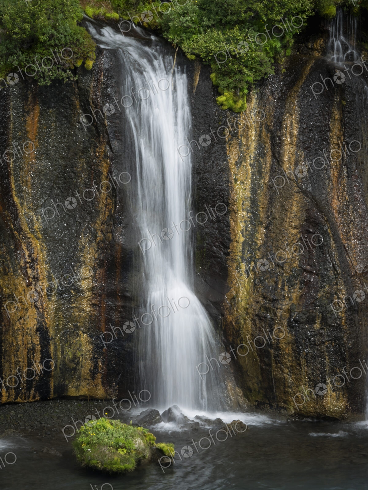 Hraunfossar waterfalls, a cascade of water over a sheer cliff into a pool.
