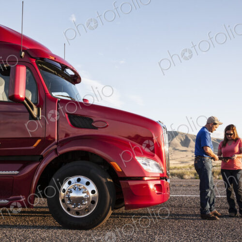 Husband and wife driving team checking their itinerary while standing in front of… Husband and wife driving team checking their itinerary while standing in front of…