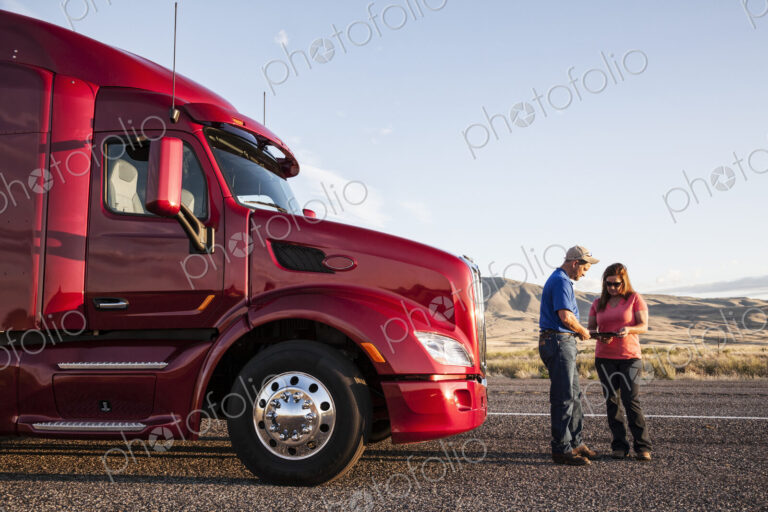 Husband and wife driving team checking their itinerary while standing in front of…