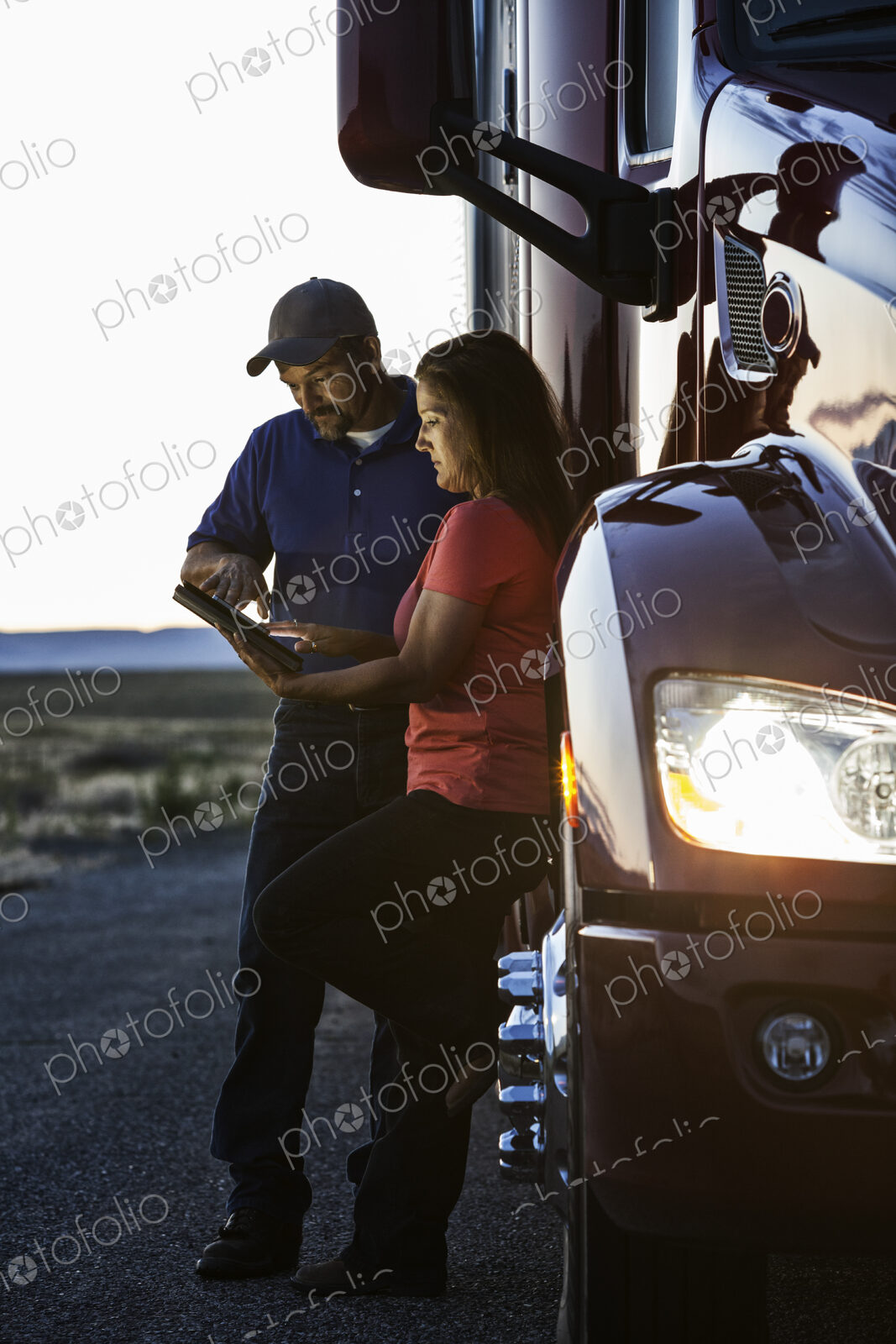 Husband and wife driving team checking their notebook computer log while standing next…