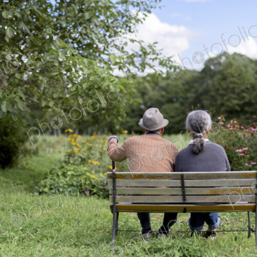 Husband and wife, rear view of elderly man wearing hat and woman sitting side by side… Husband and wife, rear view of elderly man wearing hat and woman sitting side by side…