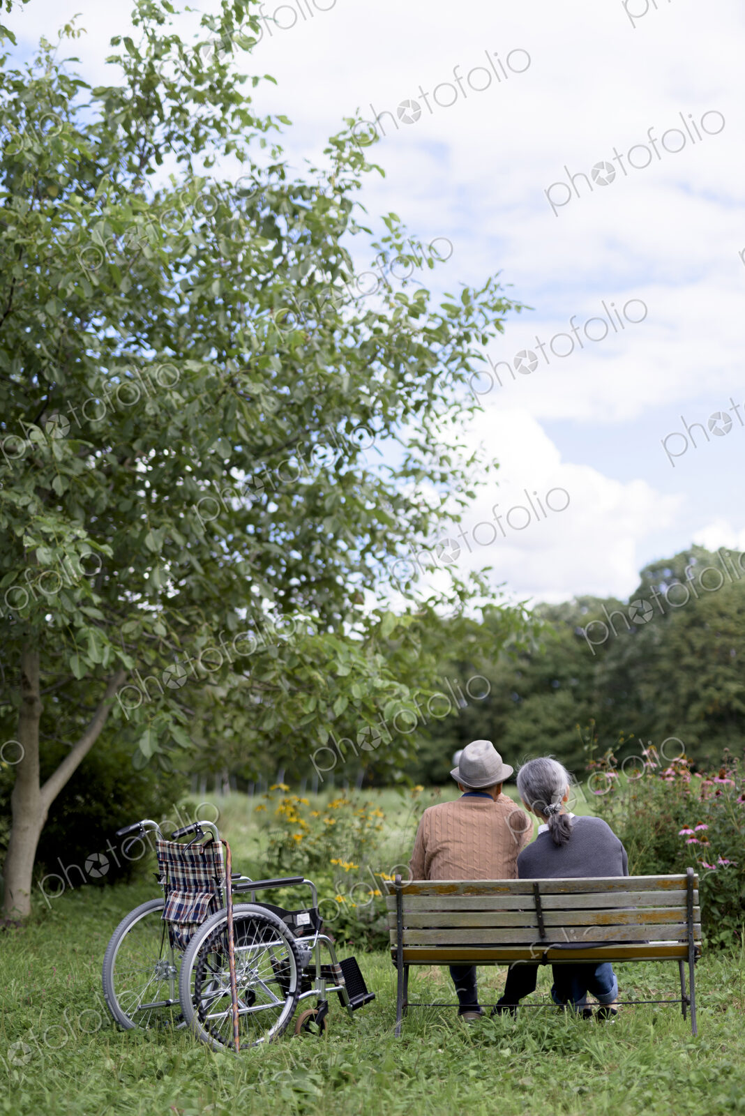 Husband and wife, rear view of elderly man wearing hat and woman sitting side by side…