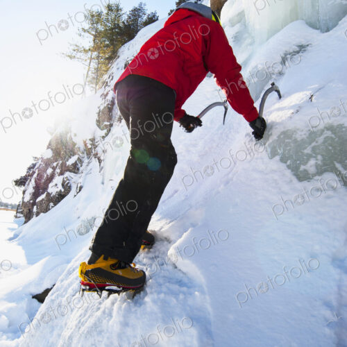Ice climber scaling snowy frozen rock formations
