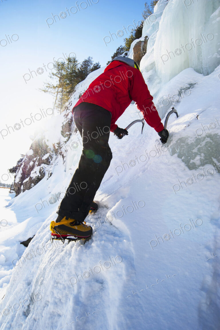 Ice climber scaling snowy frozen rock formations
