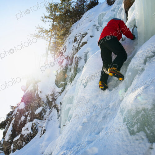 Ice climber scaling snowy frozen rock formations