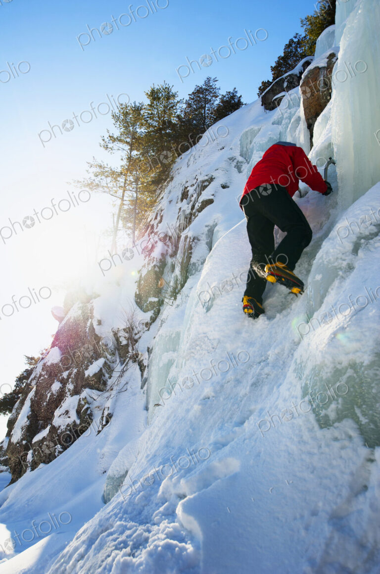 Ice climber scaling snowy frozen rock formations