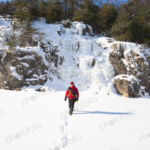 Ice climber walking toward frozen rock formations