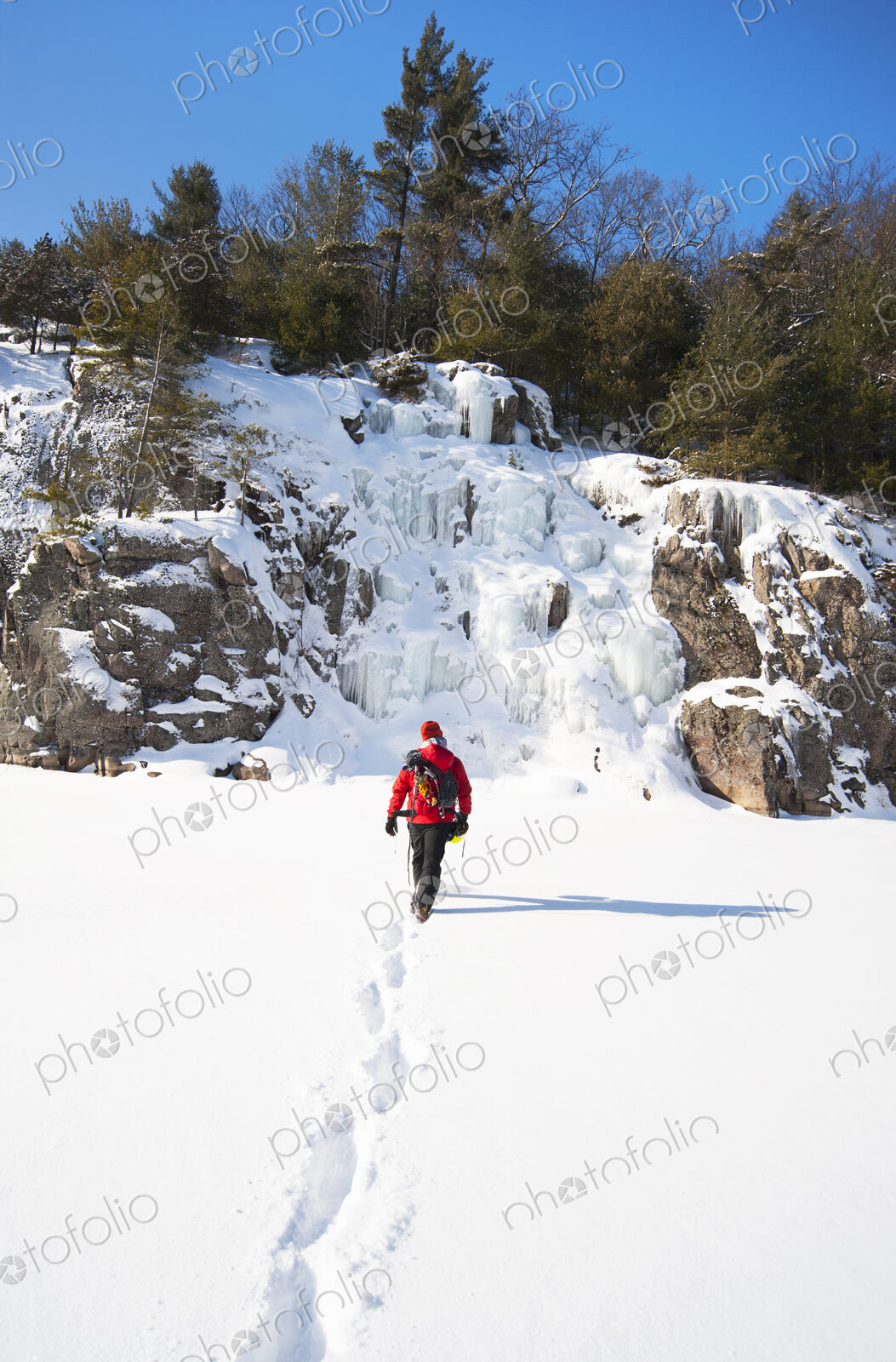 Ice climber walking toward frozen rock formations