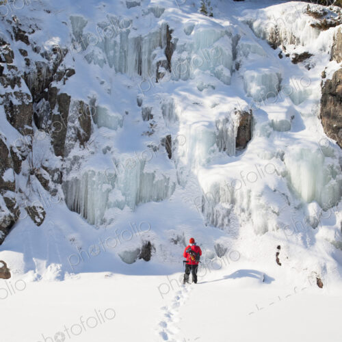 Ice climber walking toward frozen rock formations
