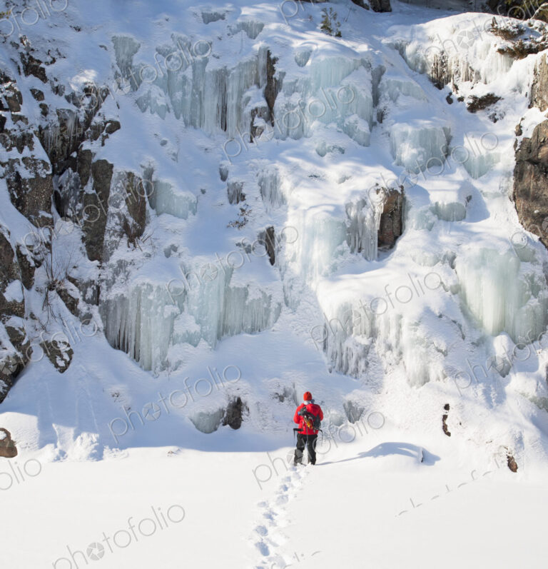 Ice climber walking toward frozen rock formations