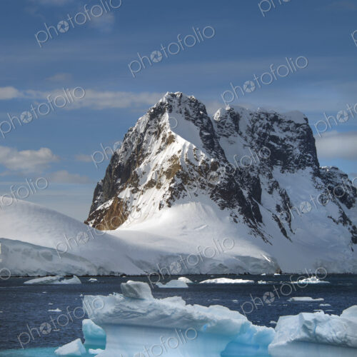 Icebergs floating in the water off the rocky shore of Antactica. Icebergs floating in the water off the rocky shore of Antactica.