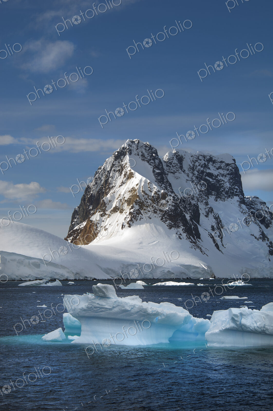 Icebergs floating in the water off the rocky shore of Antarctica.