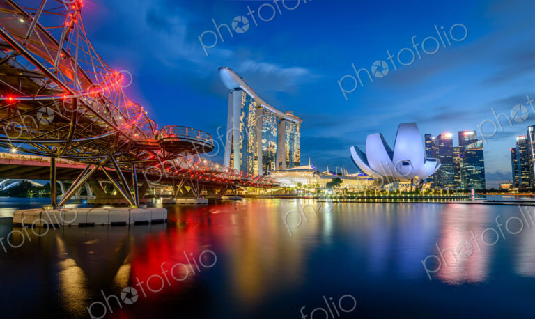 Illuminated Singapore waterfront in the evening, with Marina Bay Sands Hotel and…