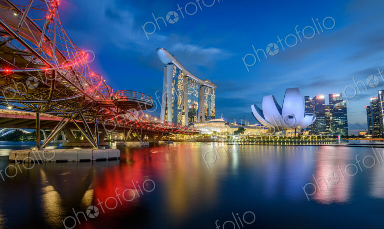 Illuminated Singapore waterfront in the evening, with Marina Bay Sands Hotel and…