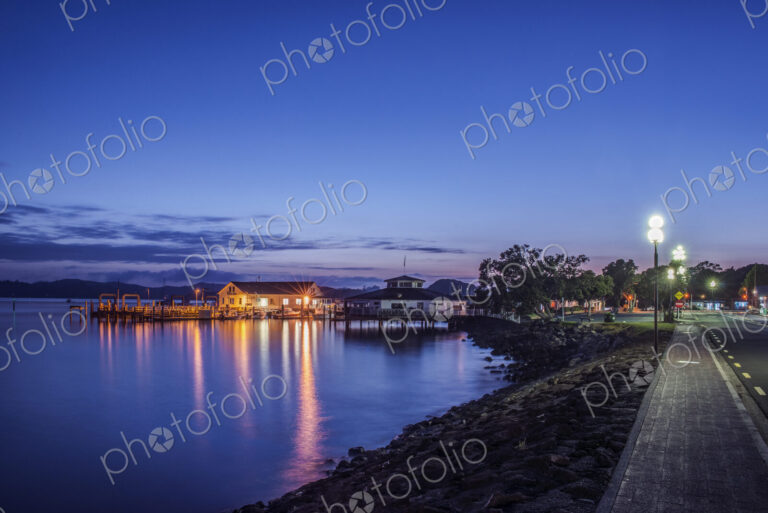Illuminated buildings on water at dawn